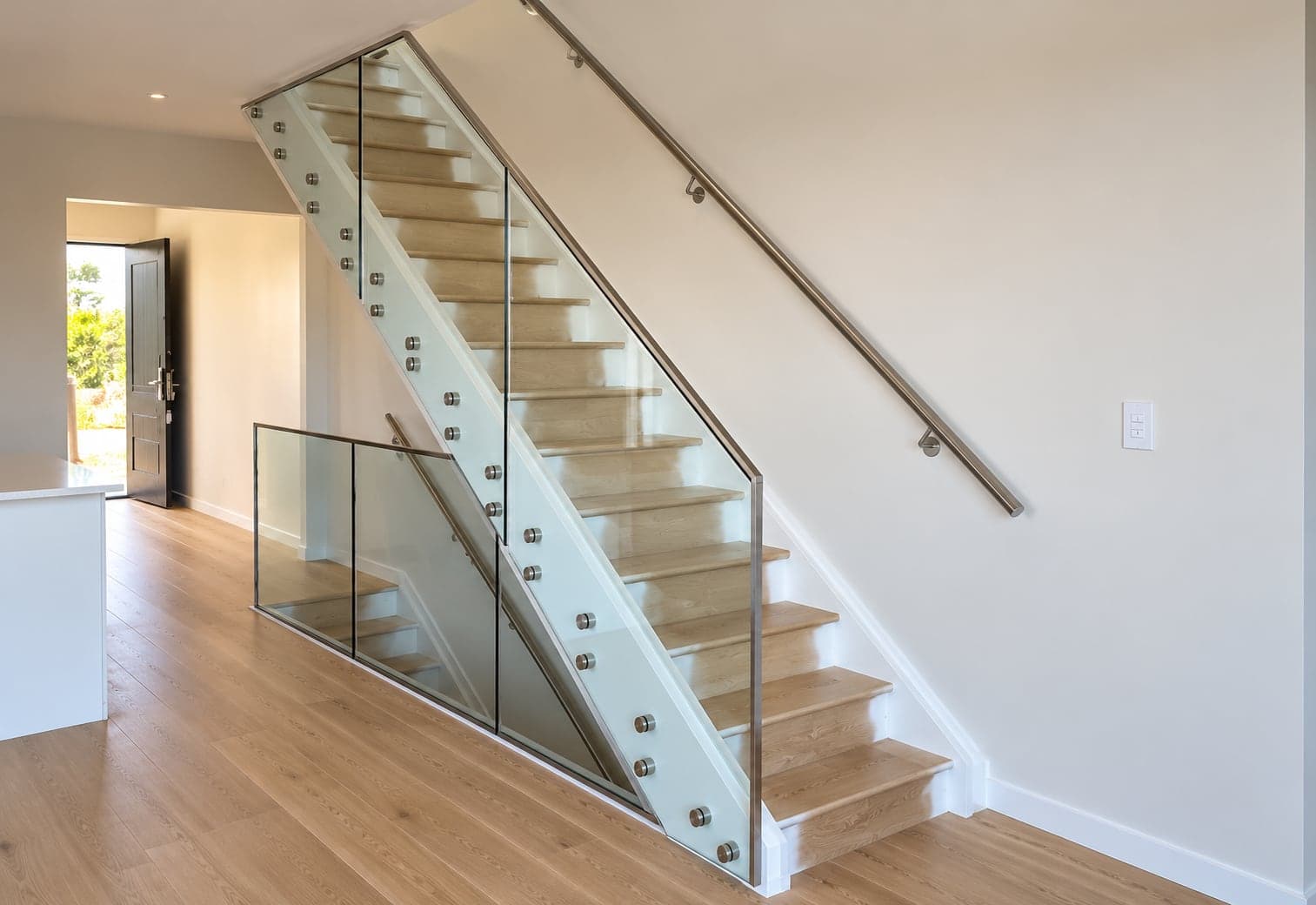 Silver-framed glass balustrade with handrail beside a timber staircase