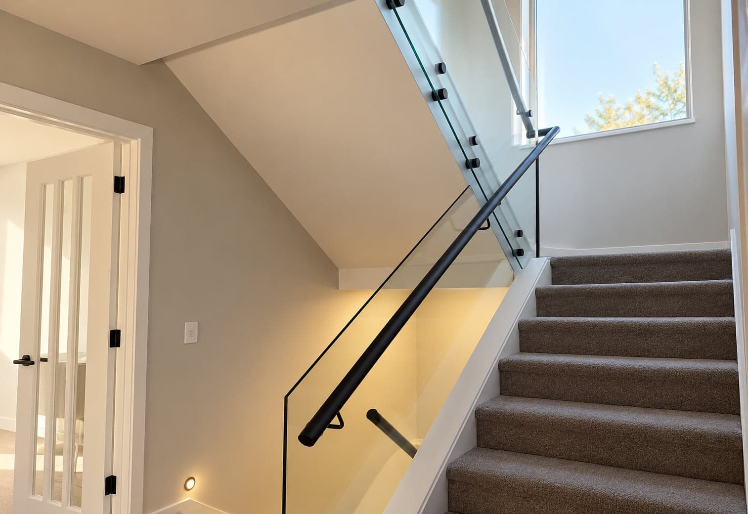 Indoor glass stair balustrade with black handrail and standoffs