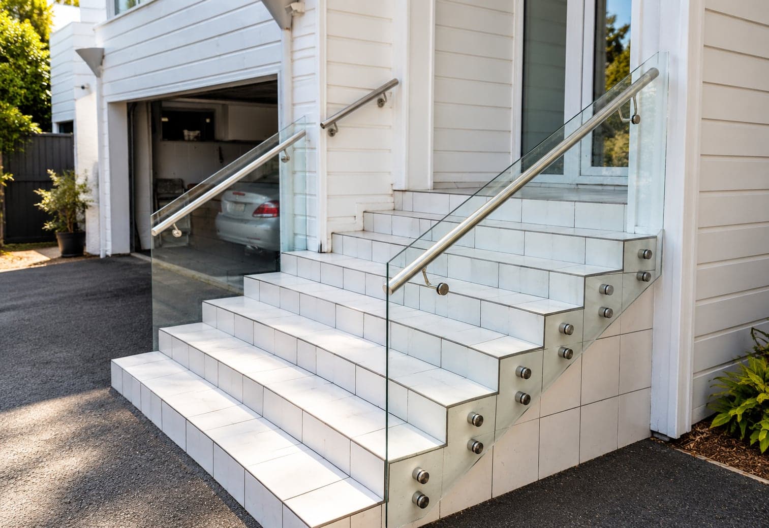 Silver handrail with glass balustrade beside outdoor tiled stairs