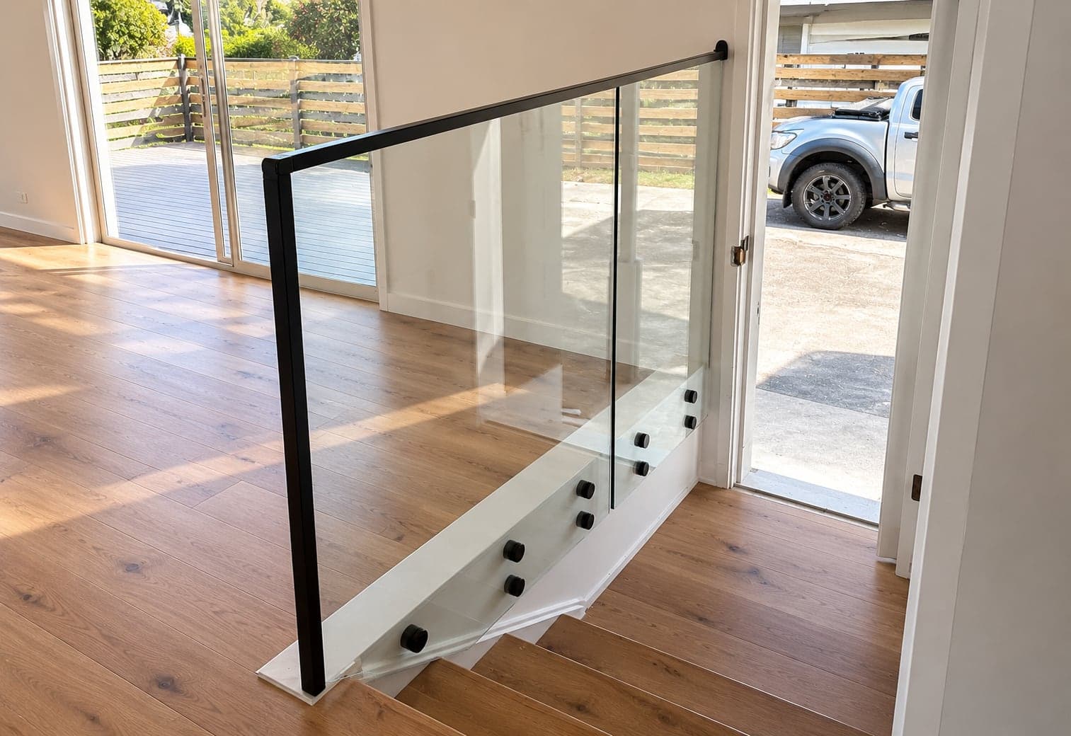 Black-framed glass balustrade beside an indoor timber staircase