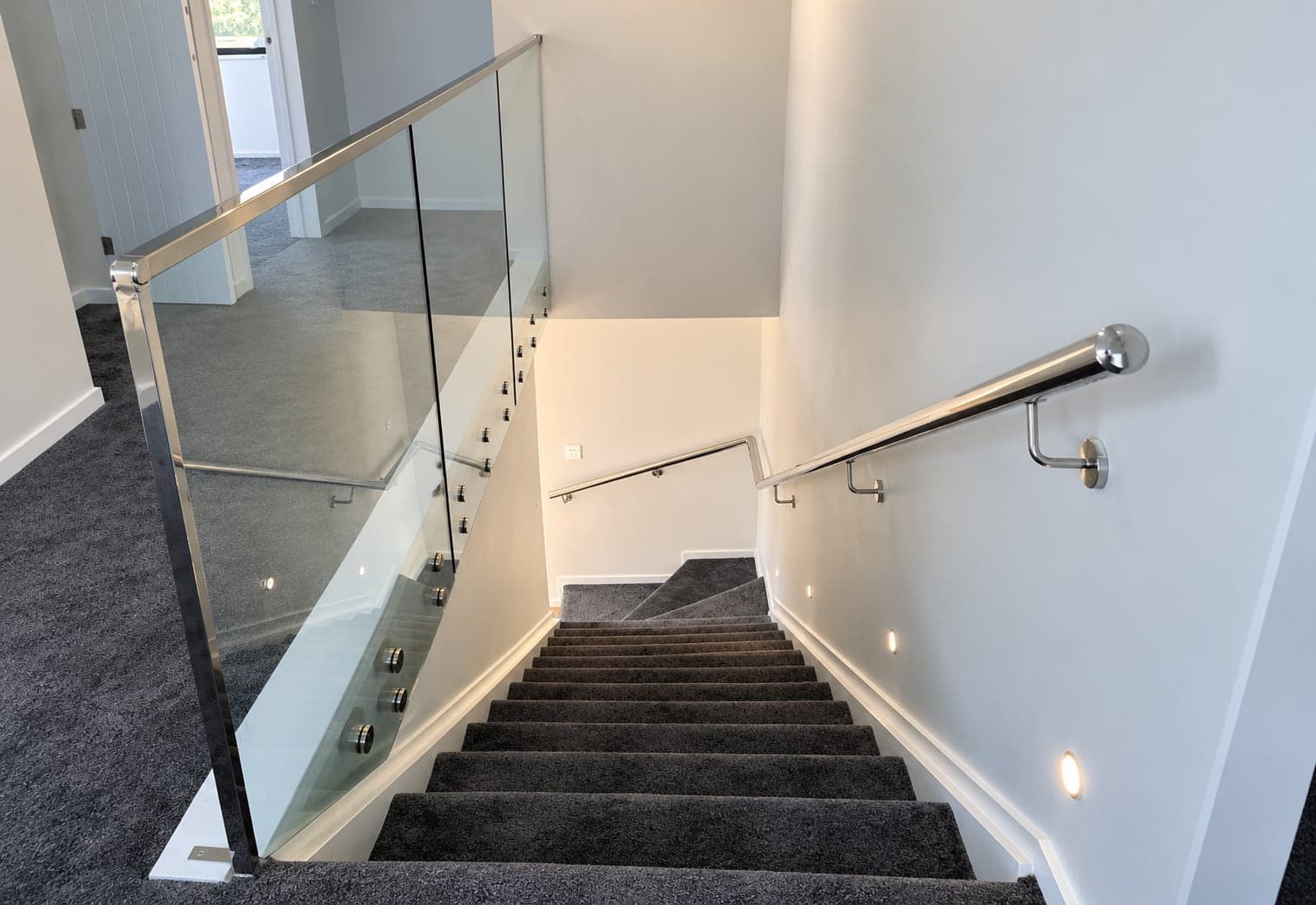 Silver handrail beside framed glass panels in a stairwell
