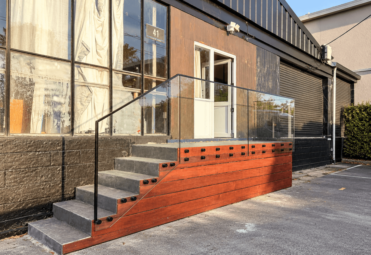 Outdoor stairs with glass panels, black standoffs, and a black frame