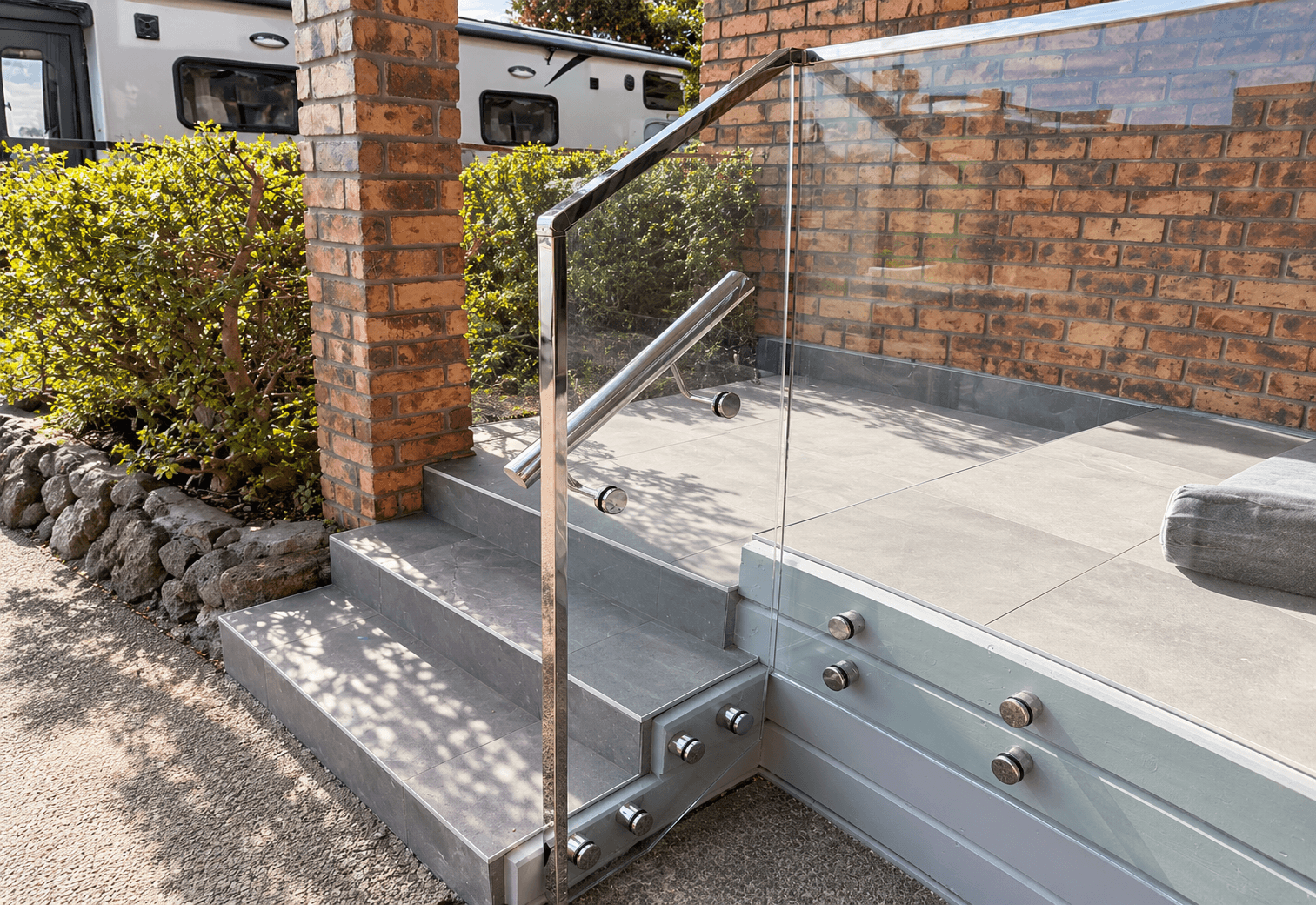 Outdoor stairs with glass panels, silver standoffs, and a silver frame