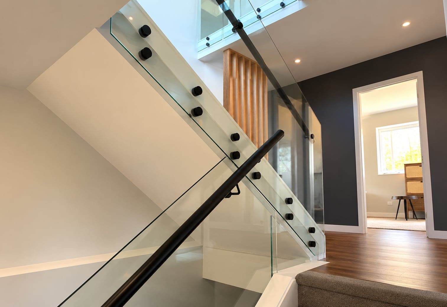 Black handrail beside glass panels on an indoor staircase