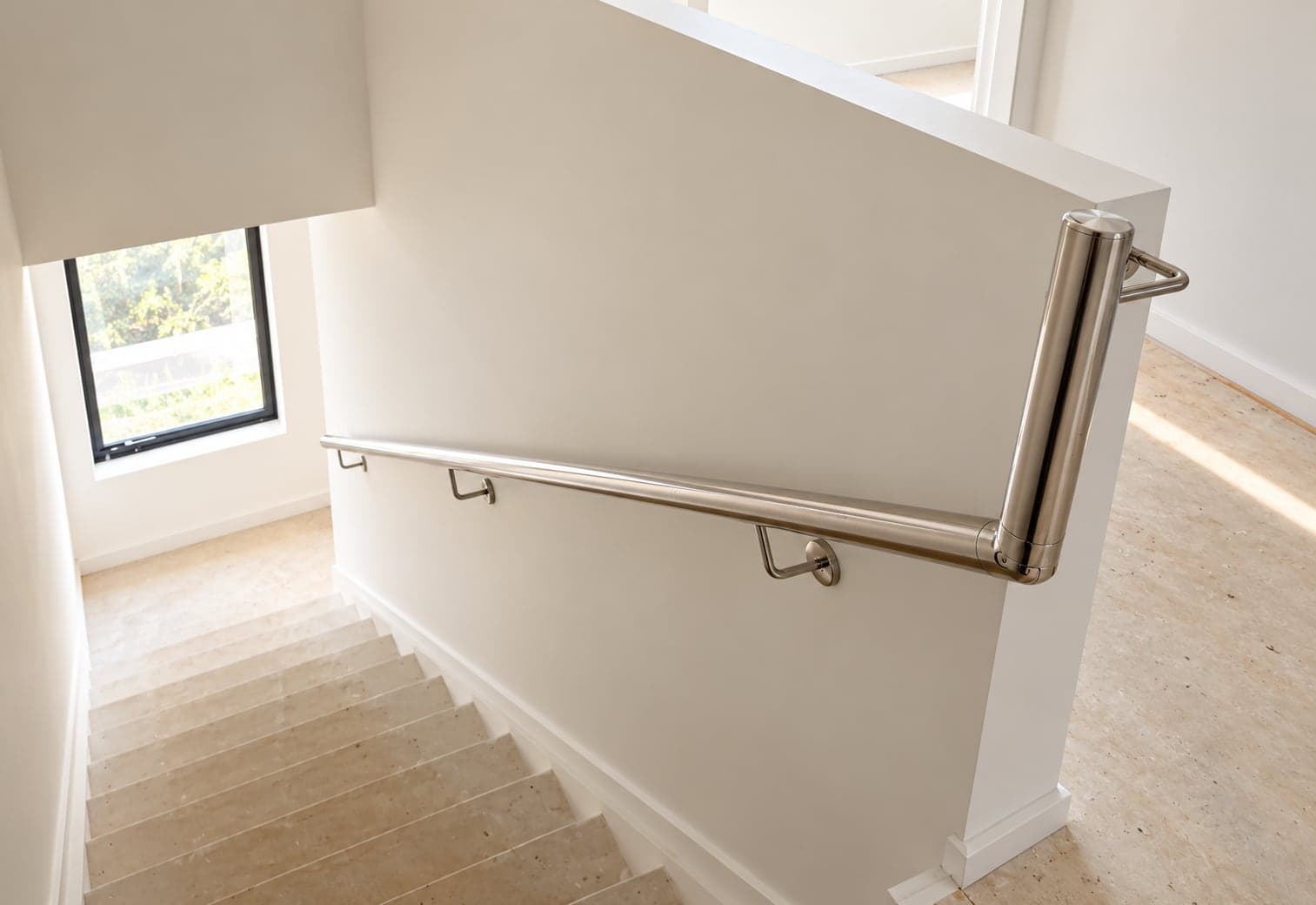 Silver handrail mounted along a light staircase