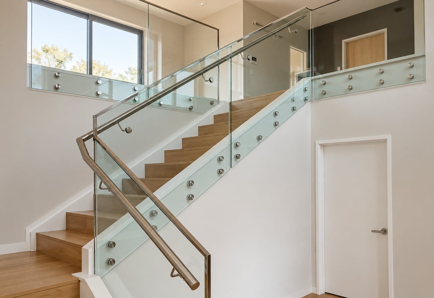 Silver handrail and glass panels beside timber stairs