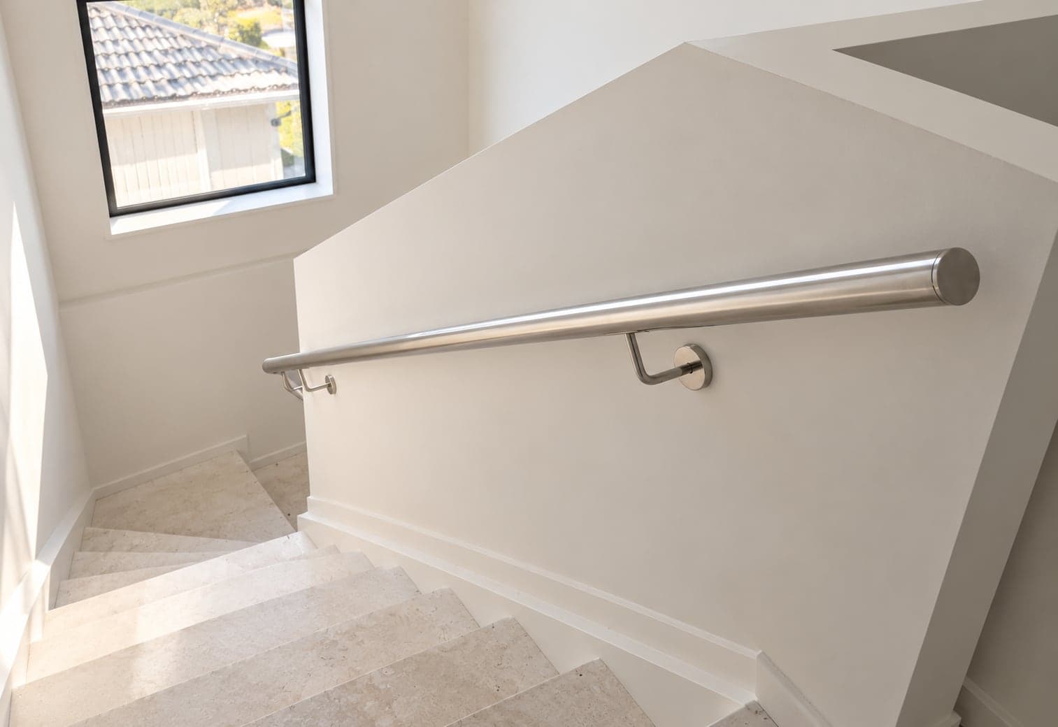 Silver wall-mounted handrail above a white staircase