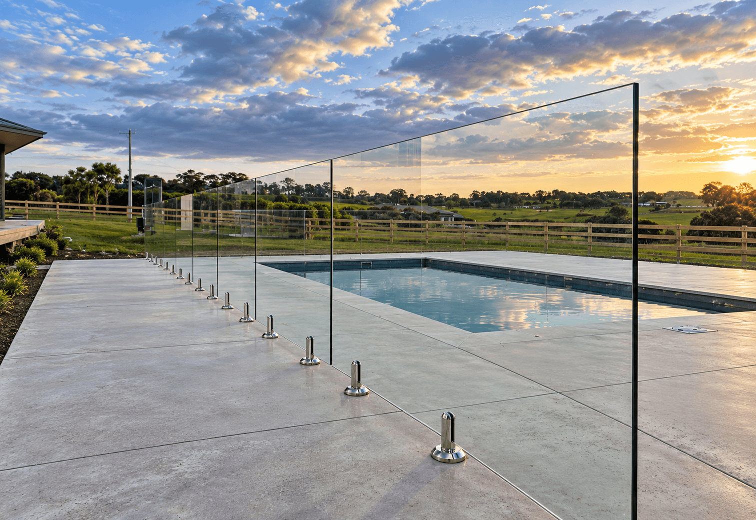 Frameless pool fence with silver spigots beside a swimming pool