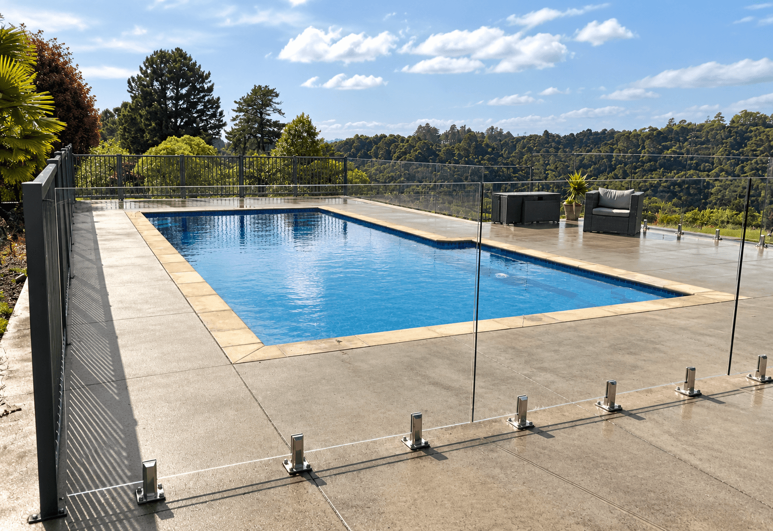 Glass pool fence with silver spigots beside a swimming pool