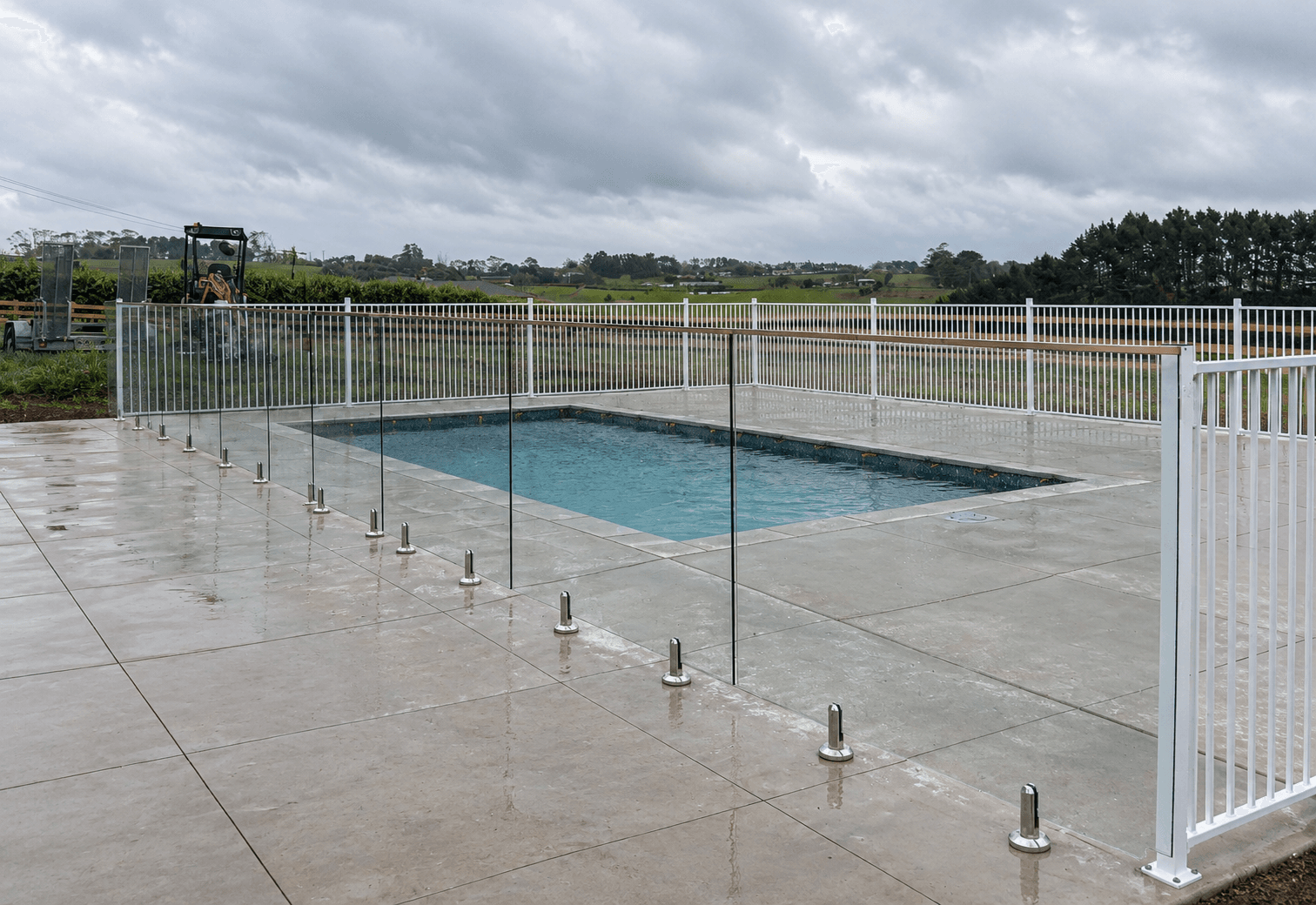 Glass pool fence with silver spigots and silver frame around a pool