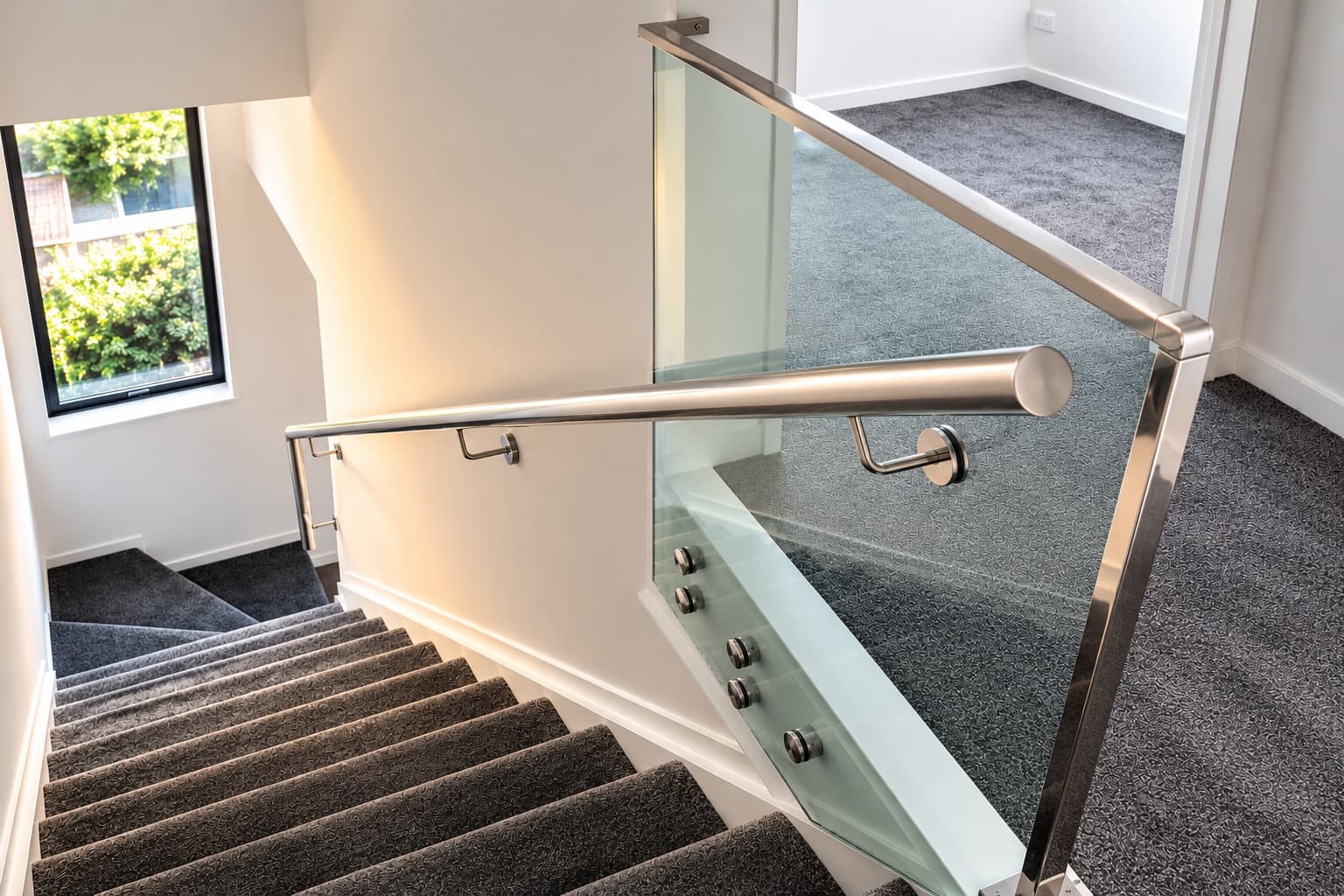 Metal handrails and glass balustrade beside an indoor staircase