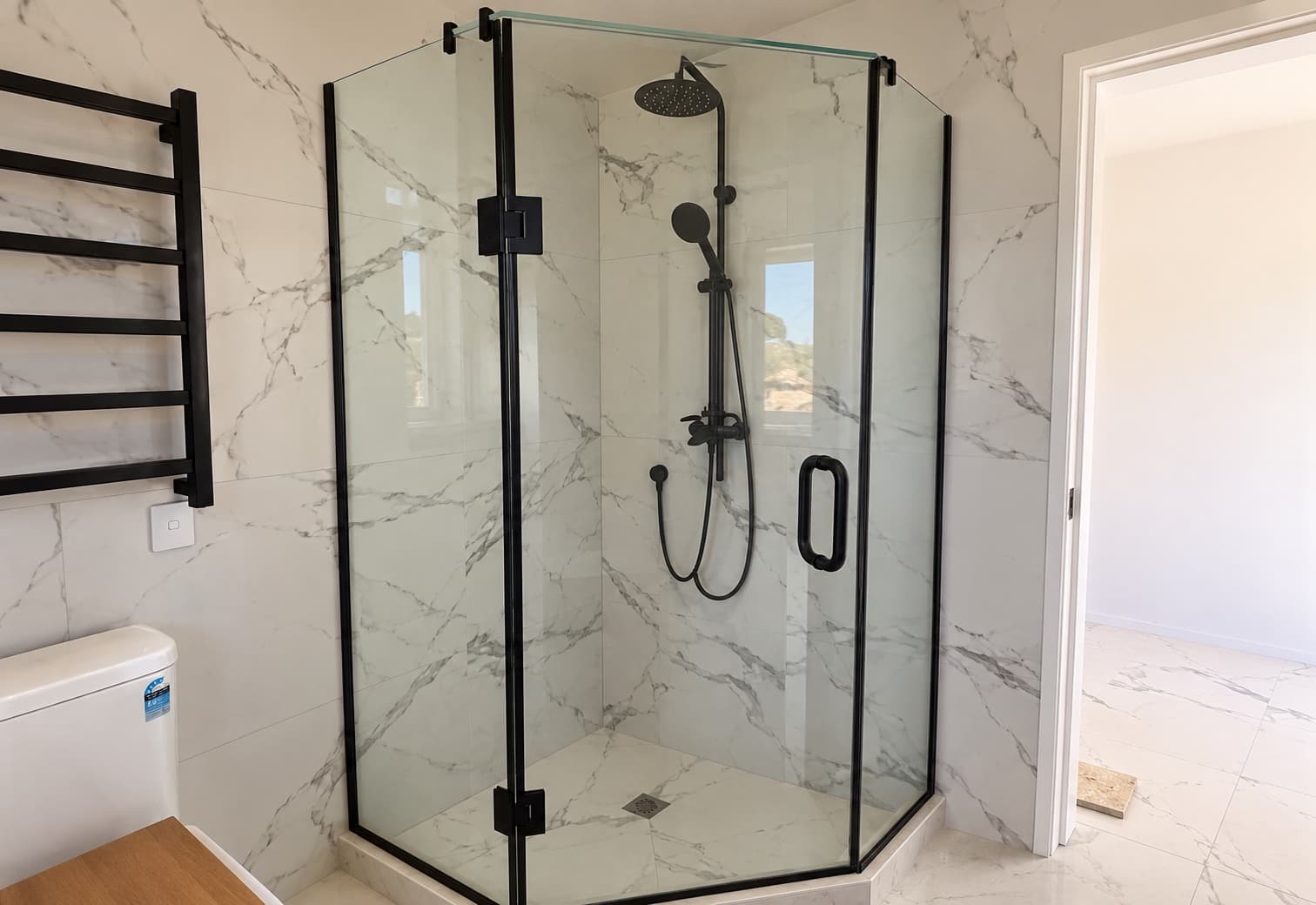 Black-framed glass shower with marble wall tiles