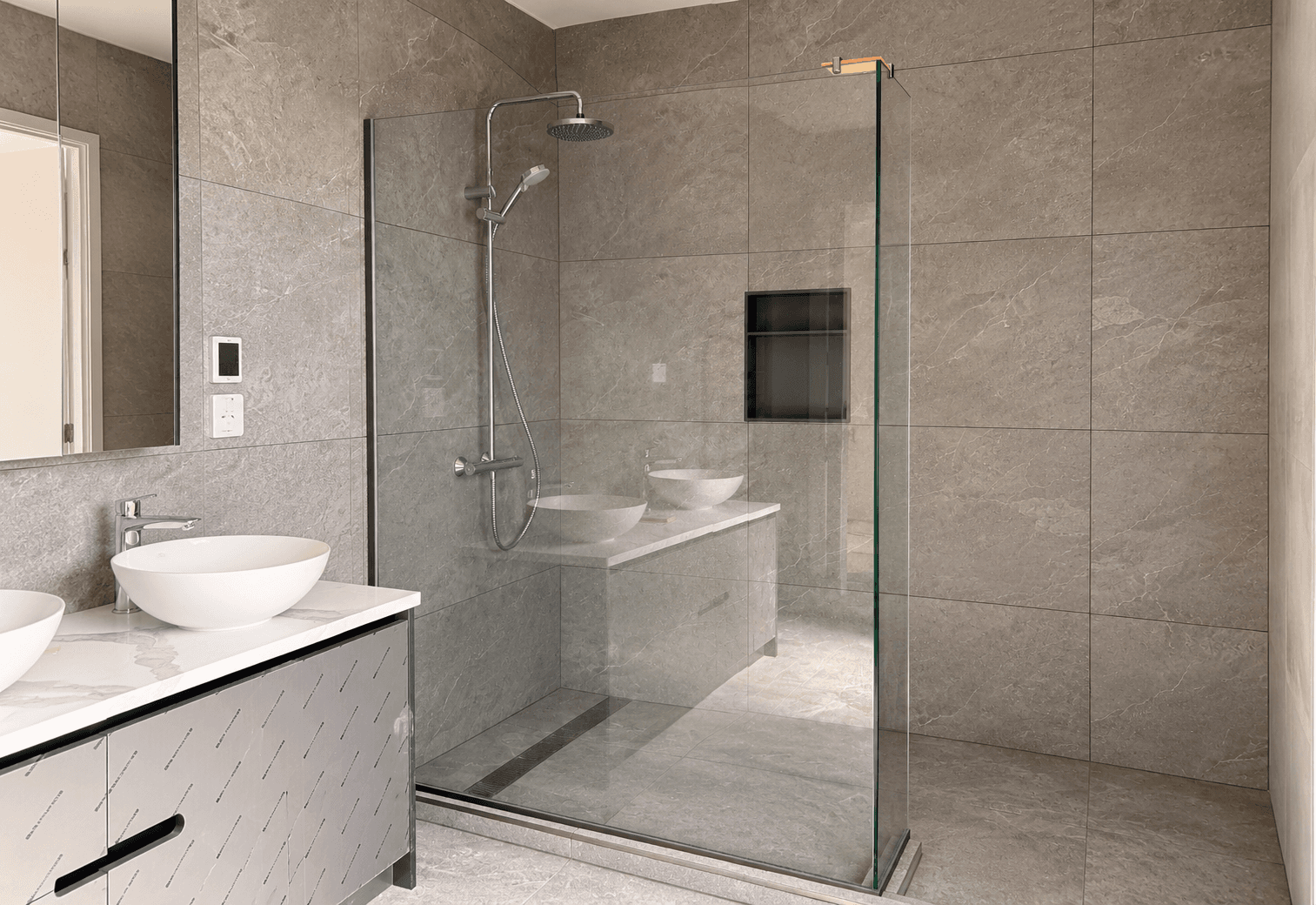 Walk-in shower enclosure with a clear glass screen and silver hardware