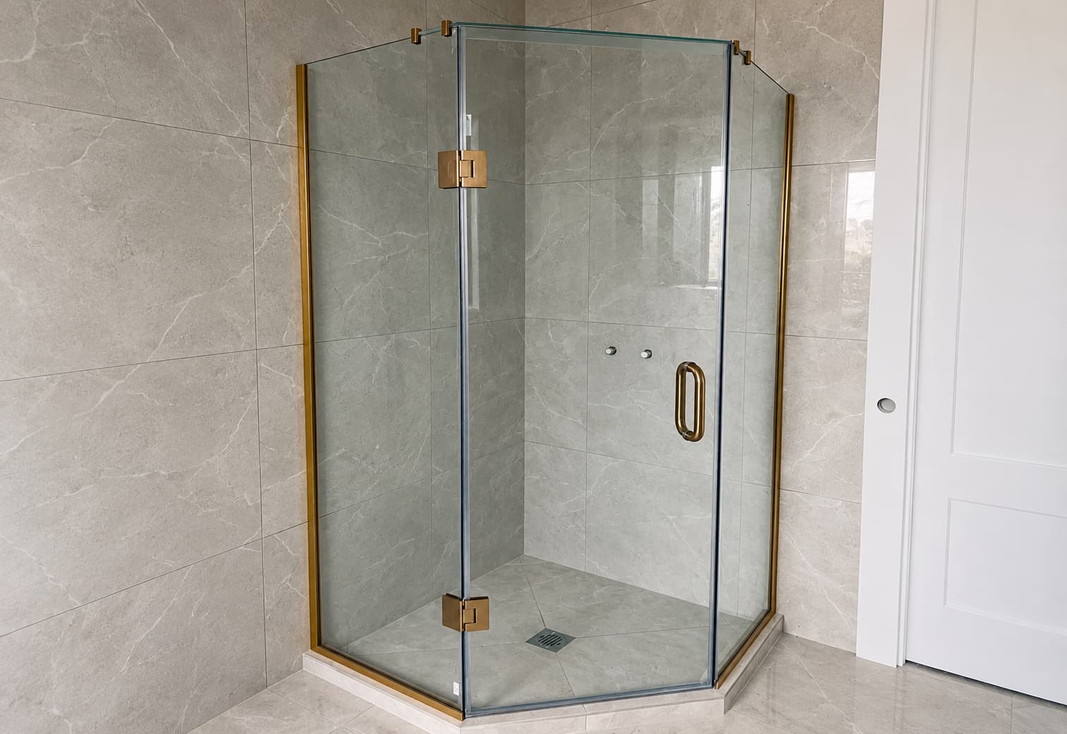 Glass shower enclosure with brass hardware and stone tile