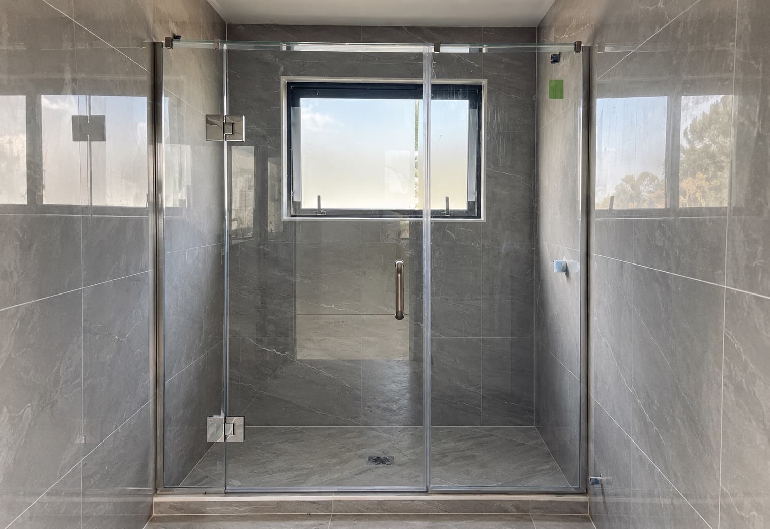 Glass shower in a marble bathroom with a frosted window